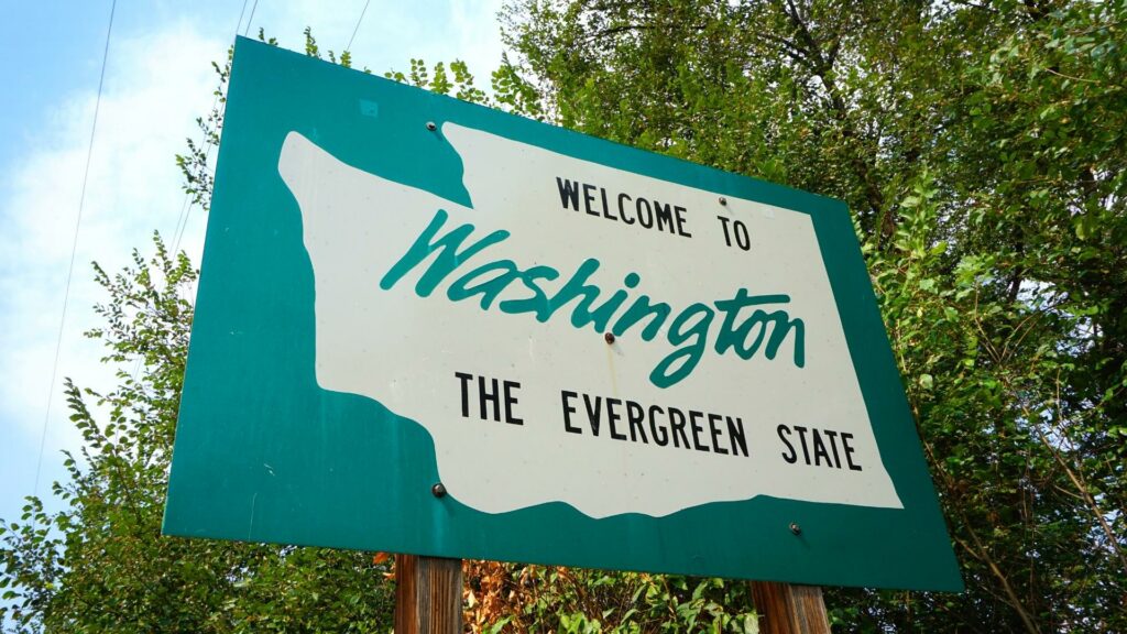 A green welcome to Washington State sign that says "the evergreen state".