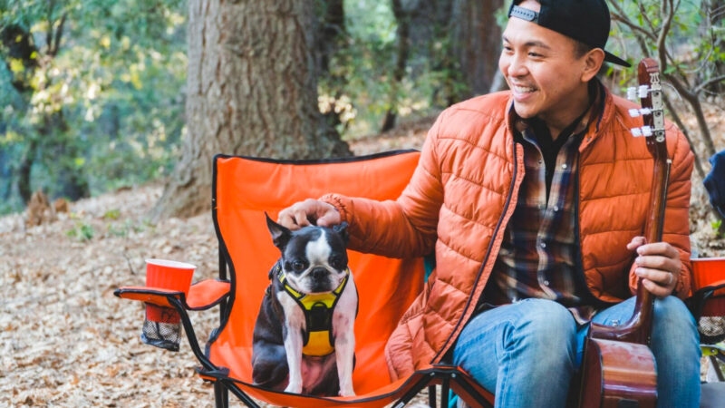 A man and his dog sitting in the best camping chairs.