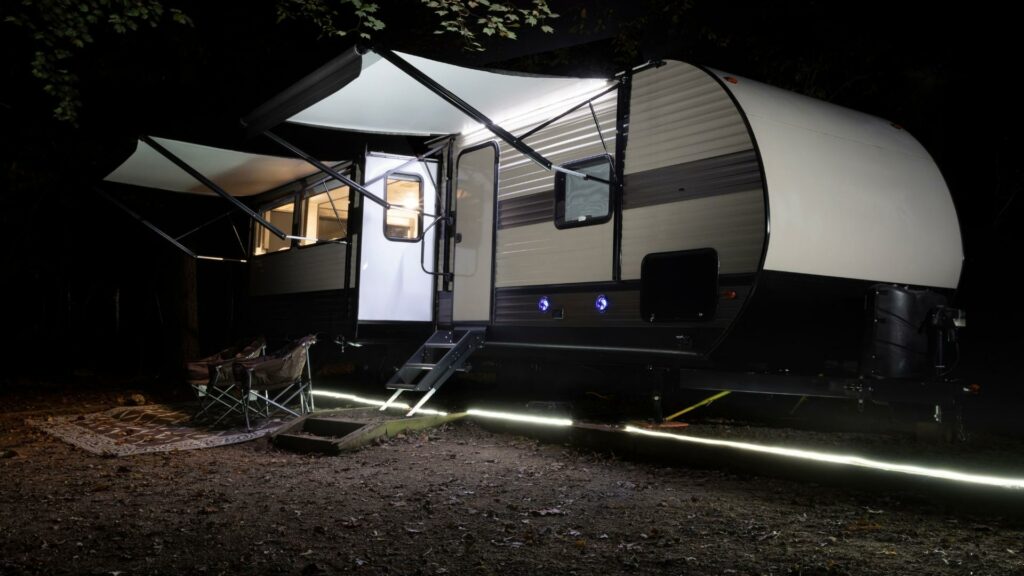 A travel trailer with its two awnings extended and LED camper awning lights under