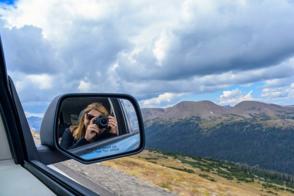 Woman in her car taking photos after entering a national park with her parks pass.