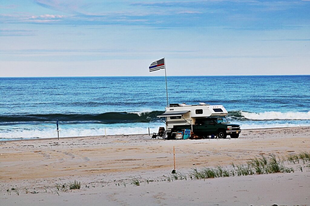 A truck camper being used at the beach after being measured off the truck to see how tall it is.