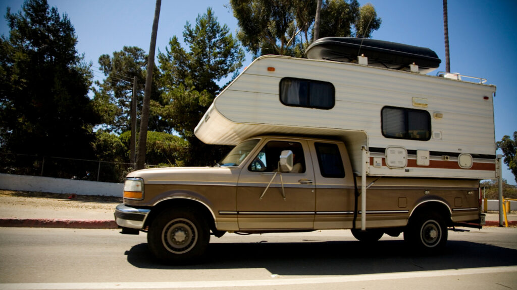A truck camper on the road after being measured off the truck to see how tall it is.