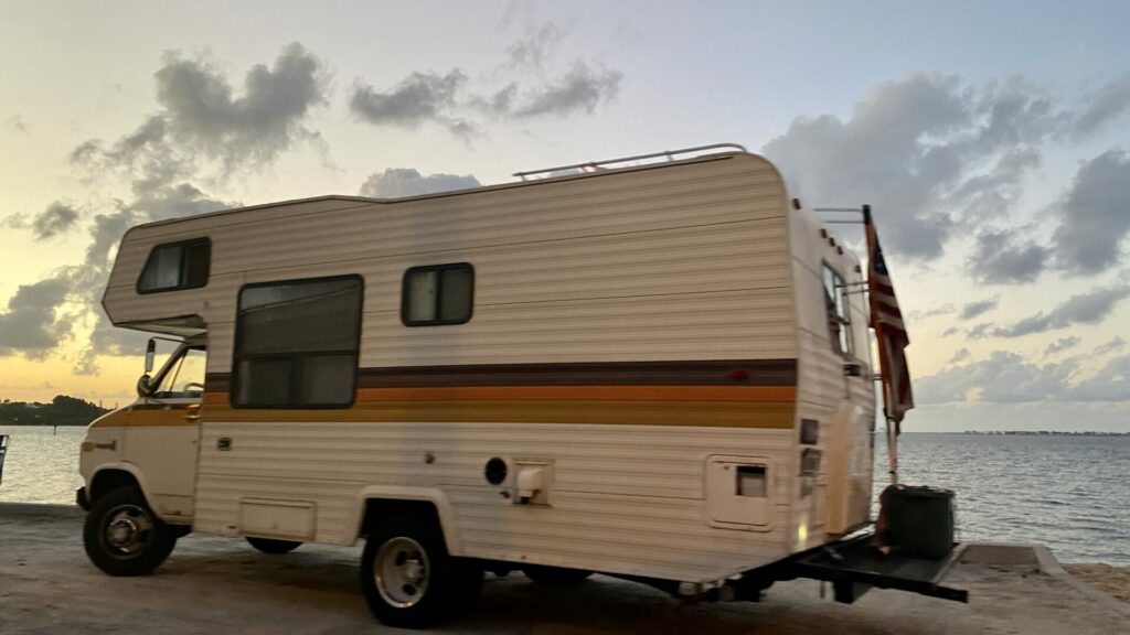 An old RV stealth camping on the beach in a public area