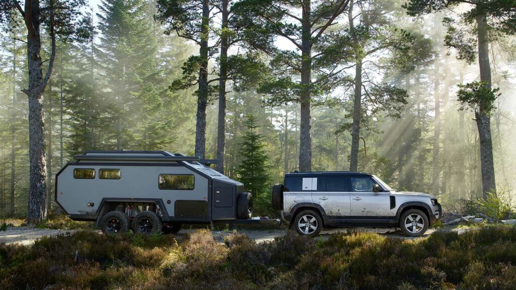 one of the best SUV for towing, the Land Rover Defender towing a travel trailer in the woods 