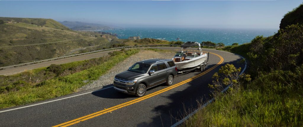 The Ford Expedition towing a boat up a windy road 