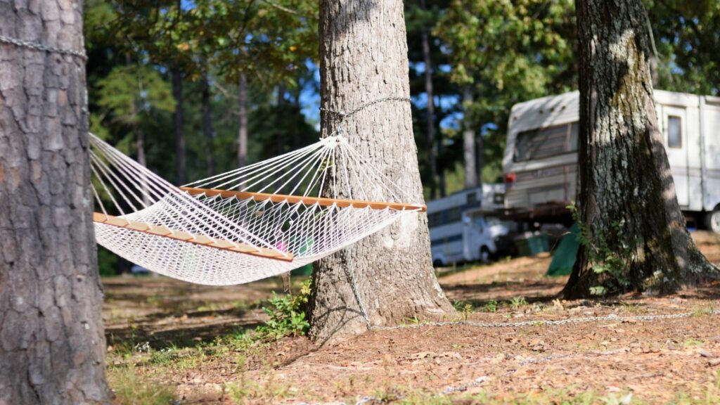 An empty hammock setup between two trees with RVs in the background