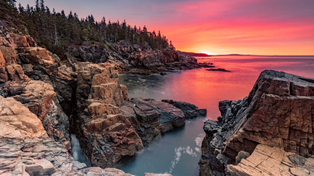 Acadia National Park at sunset with jagged rocks along the water 