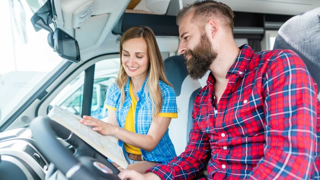 A woman sitting in the passenger seat of an RV showing the driver a map 