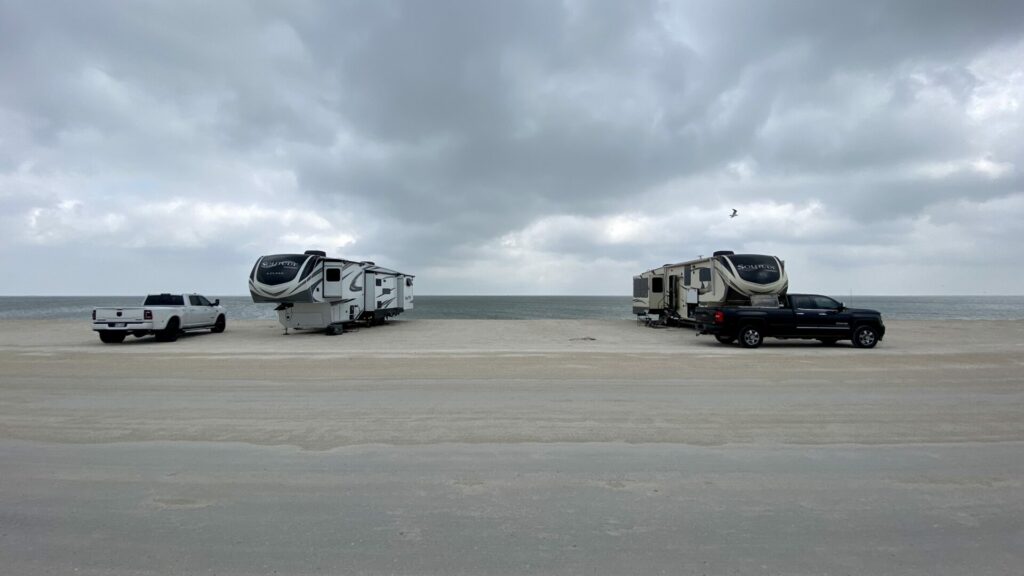 Two fifth wheels boondocking on the beach with the ocean behind them