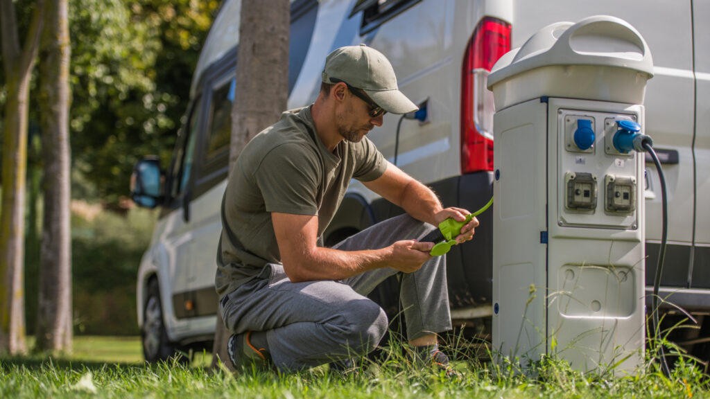 A man setting up his RV to an electrical hookup