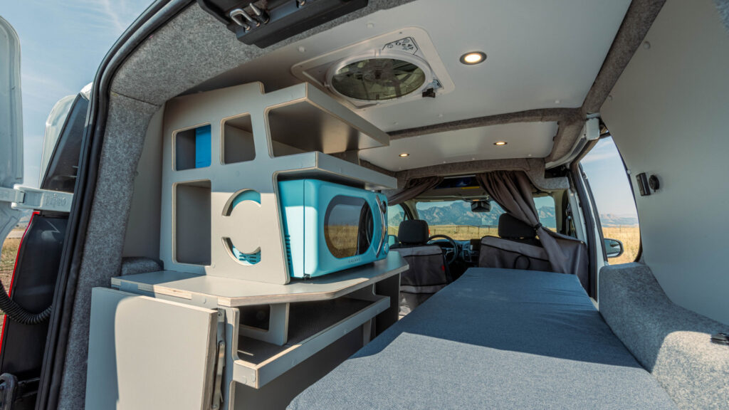 A bedroom/kitchen area in a Ford Transit Connect camper