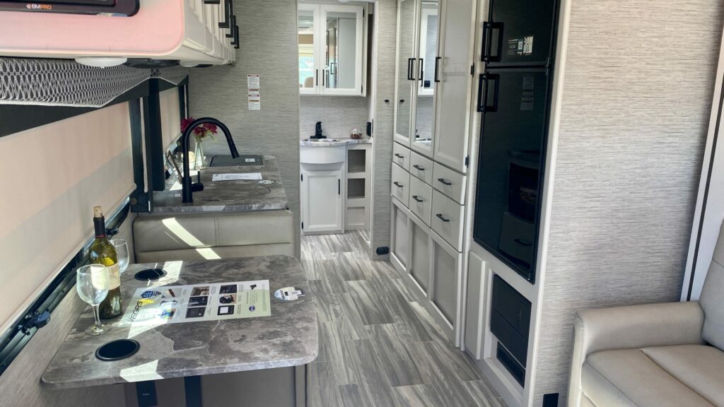 Interior picture of the Thor Vegas small Class A motorhome showing the kitchen, bathroom, and dinette. 