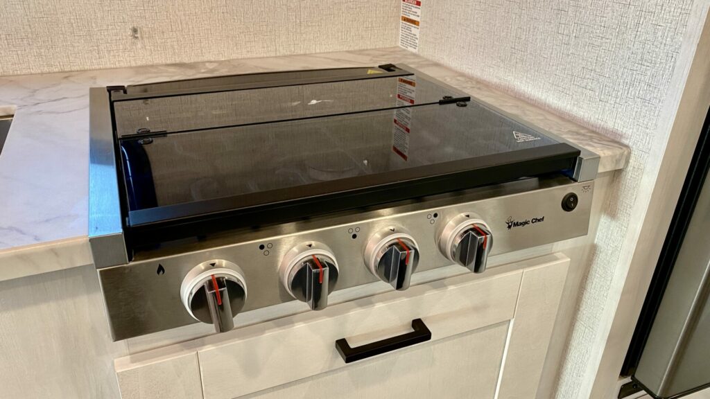 An RV propane stove with the igniter button and four burner options 