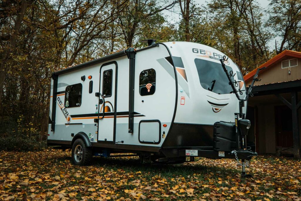 A Geo Pro by Rockwood Campers parked in a driveway with orange leaves on the ground and trees in the background