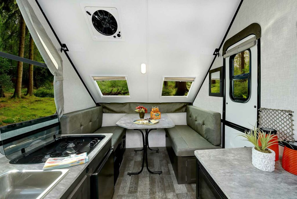 Interior of a hard sided A frame camper by Rockwood showing the dinette, kitchen, and windows