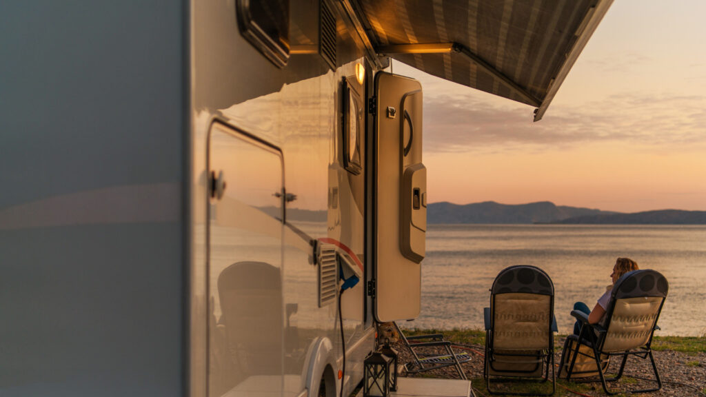 Man sitting by the beach under his camper awning