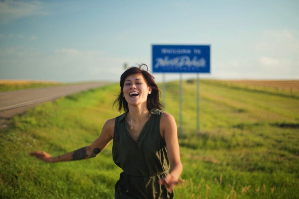 Girl running by a north dakota sign after visiting one of the national parks