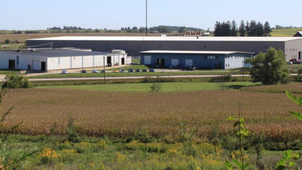 The HWH factory in Iowa with green fields in front and a large buildings in the background 