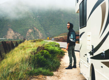 Man standing next to the camper on the road.