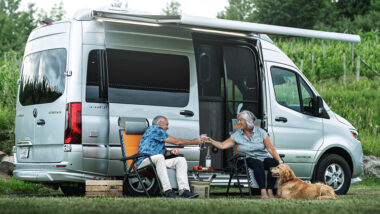 A couple and their dog sitting outside their Airstream Interstate 19