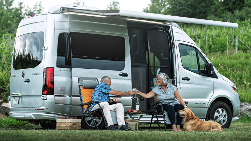 A couple and their dog sitting outside their Airstream Interstate 19