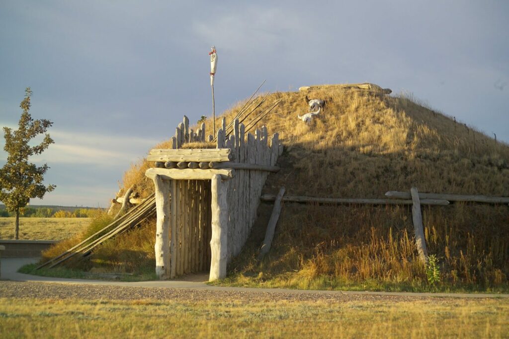 A grass hut with a wooden entry at the Knife River Indian Villages National Historic Site