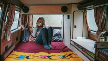 A girl drinking coffee inside her utility trailer camper