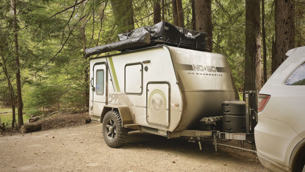 A Nobo Camper attached to a vehicle out in the woods