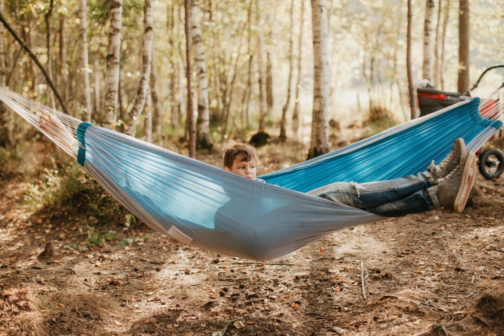 A baby and his parent in a hammock after setting up their baby camping gear