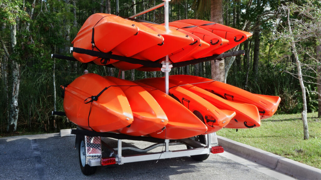 Multiple kayaks attached to a kayak trailer outside