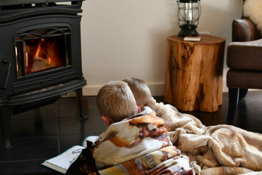Kids staying warm in front of their RV wood stove