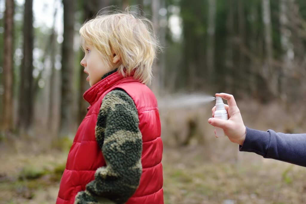 A kid being sprayed by his parent with mosquito repellent device
