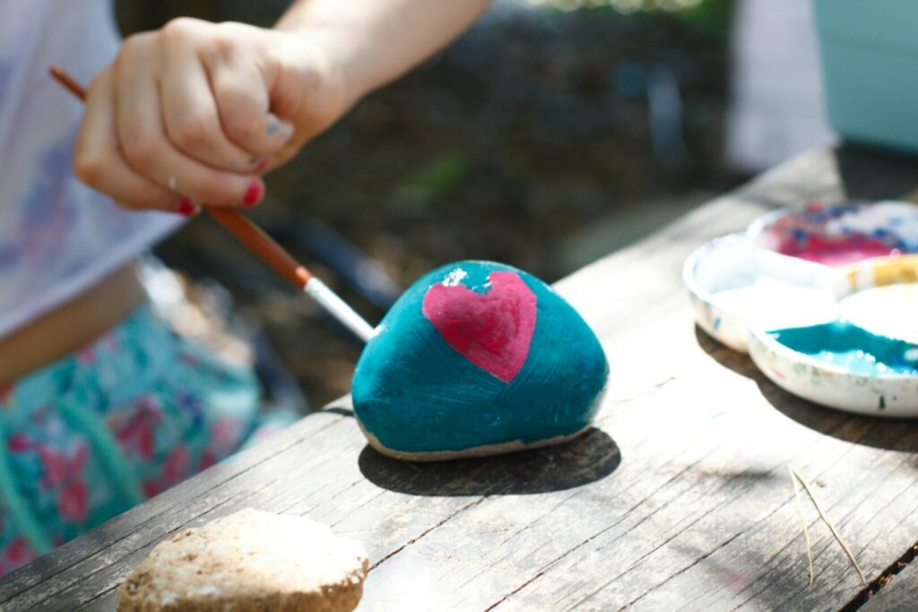 A kid painting a rock as one of the camping crafts activities