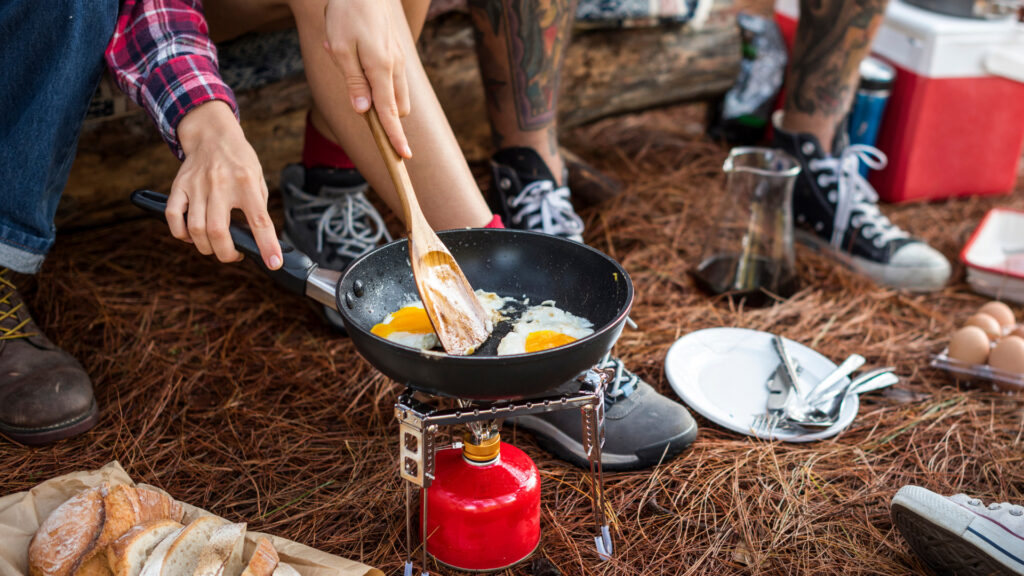 A group of friends making eggs near their RV outdoor kitchen