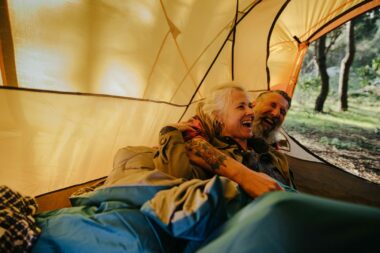 A couple laughing at camper van jokes in their tent