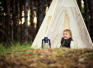 A baby happy because of his baby camping gear while camping