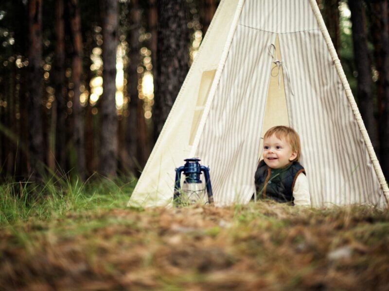 A baby happy because of his baby camping gear while camping