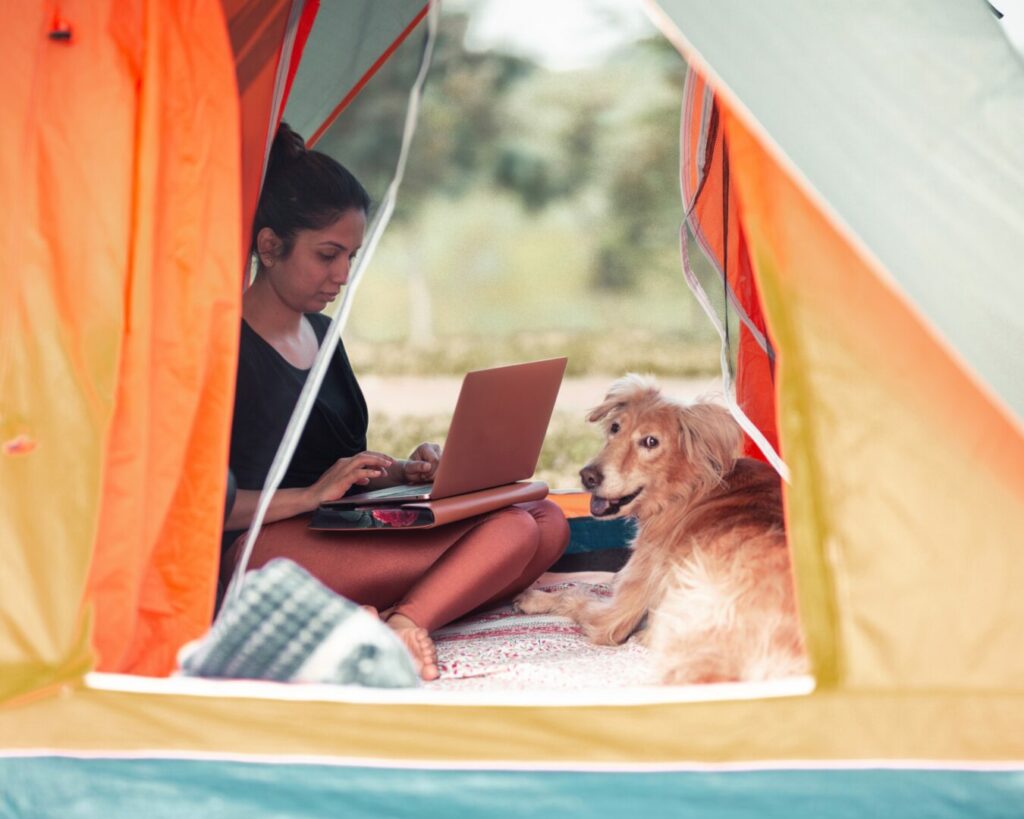 A woman using her starlink RV internet while camping with her dog