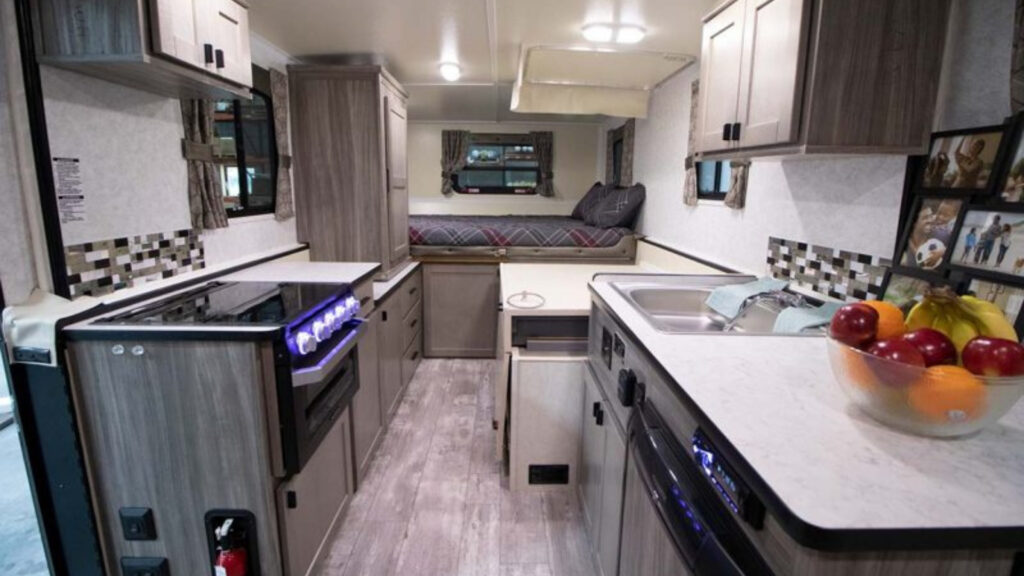 Inside a bedroom and kitchen area of a 2720 Series TrailManor RV 