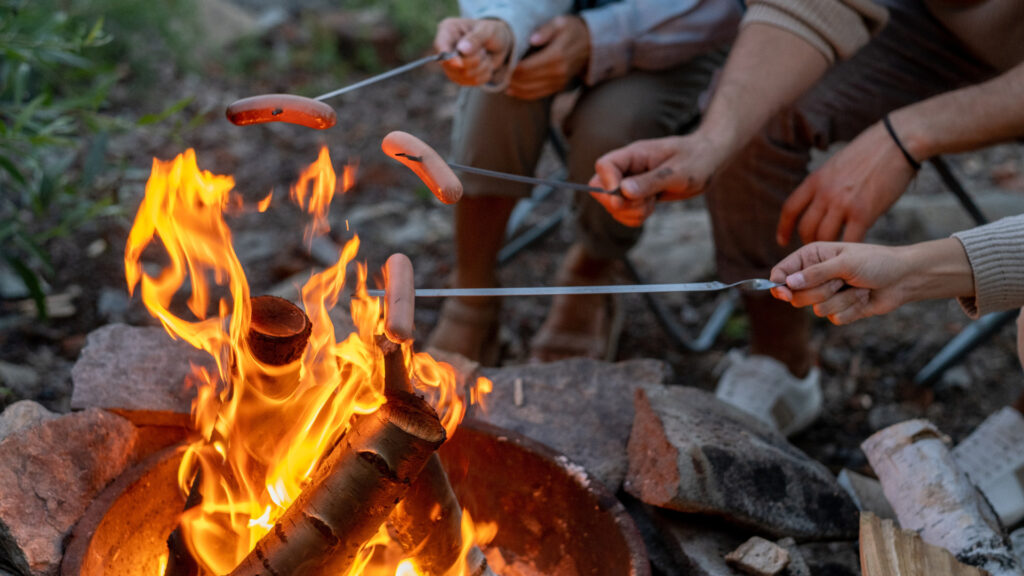 A group of friends cooking over a campfire, fully prepared with a RV fire extinguisher