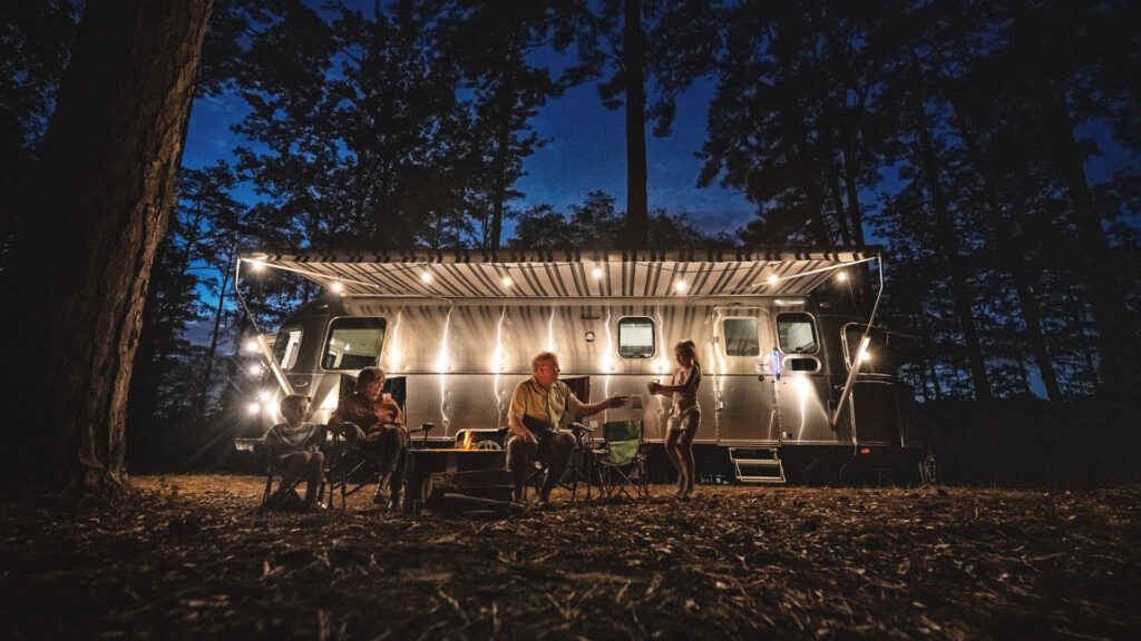 A family sitting outside of their used airstream RV that they got for sale
