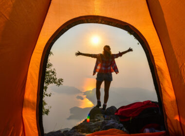 A person standing outside of their tent with screen room