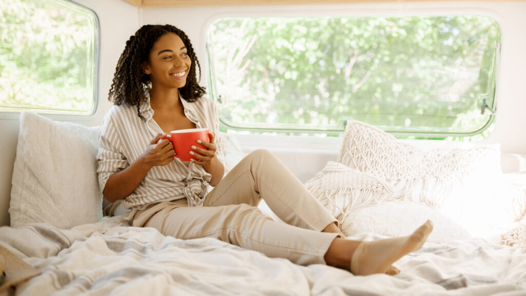 A woman sitting on her short queen mattress enjoying her coffee