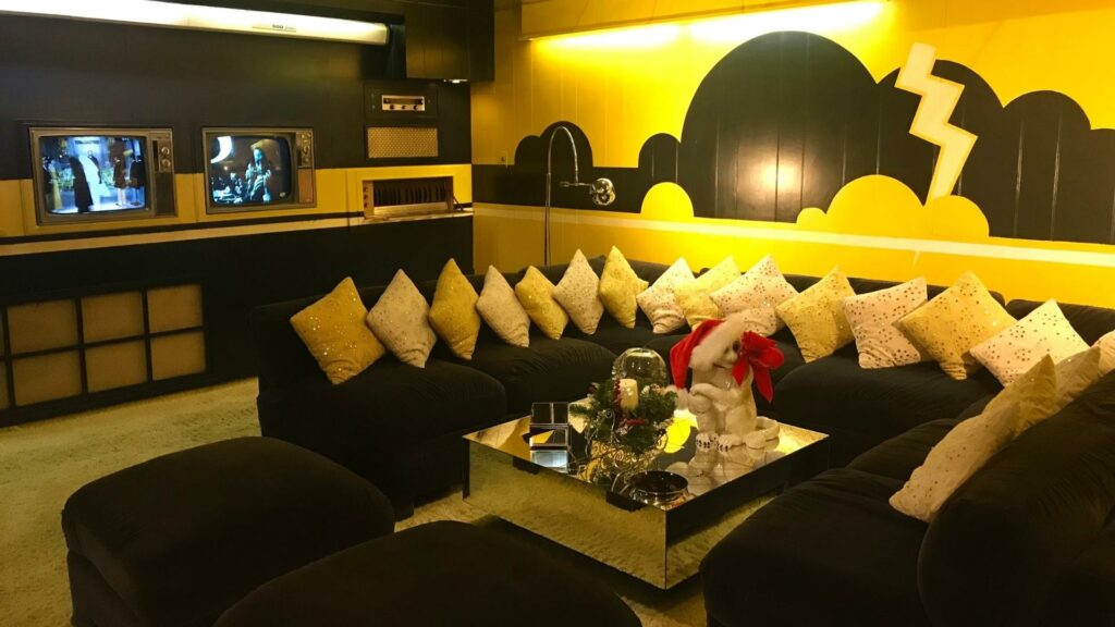 The basement living room in Graceland with yellow walls and a black couch