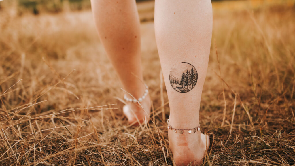 A girl outside showcasing her camping tattoo of the woods