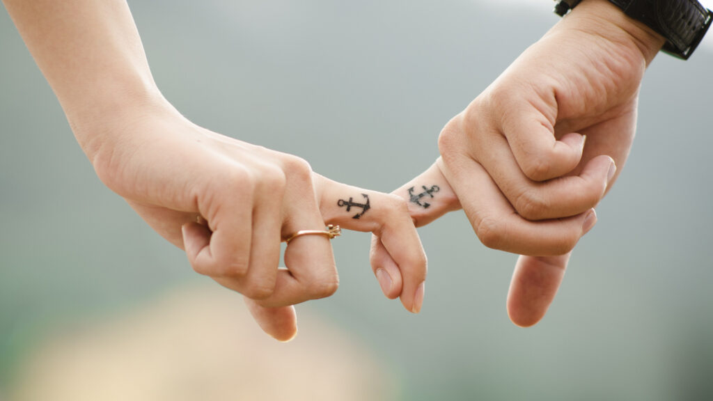 A couple holding pines with their matching camping tattoos of anchors 