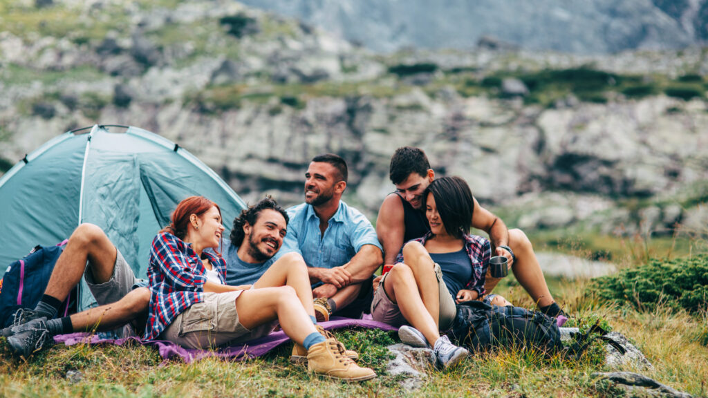 A group of friends sitting together on one of the best camping blankets