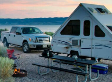 An RV with azdel panels attached to a truck parked outside during sunset