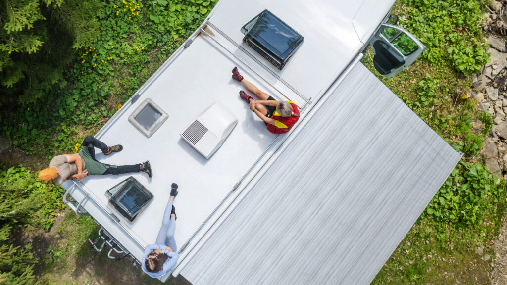 A group of friends sitting on top of their RV around their low profile rv air conditioner