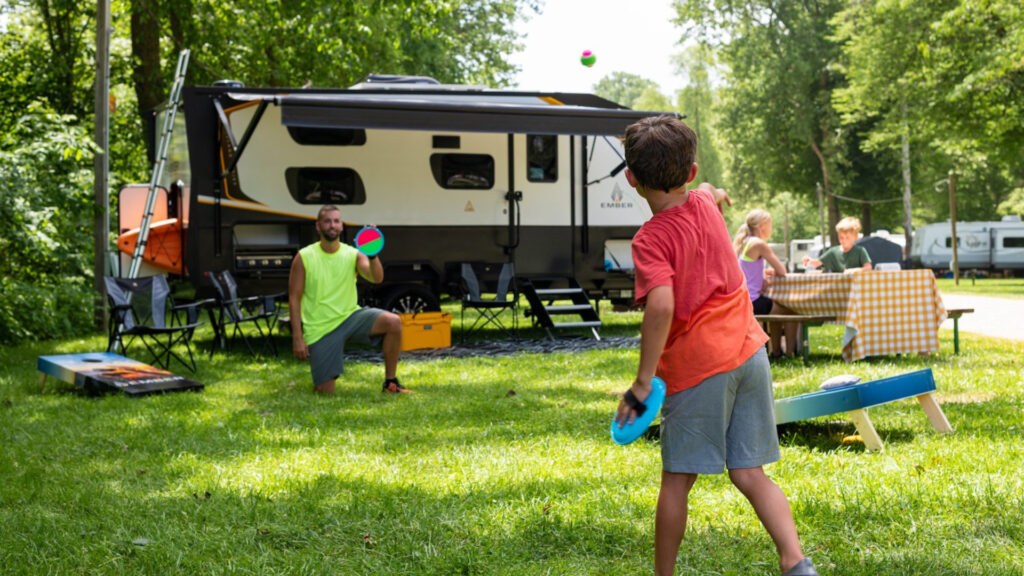 A family playing and enjoying a picnic at an RV park by their Ember RV
